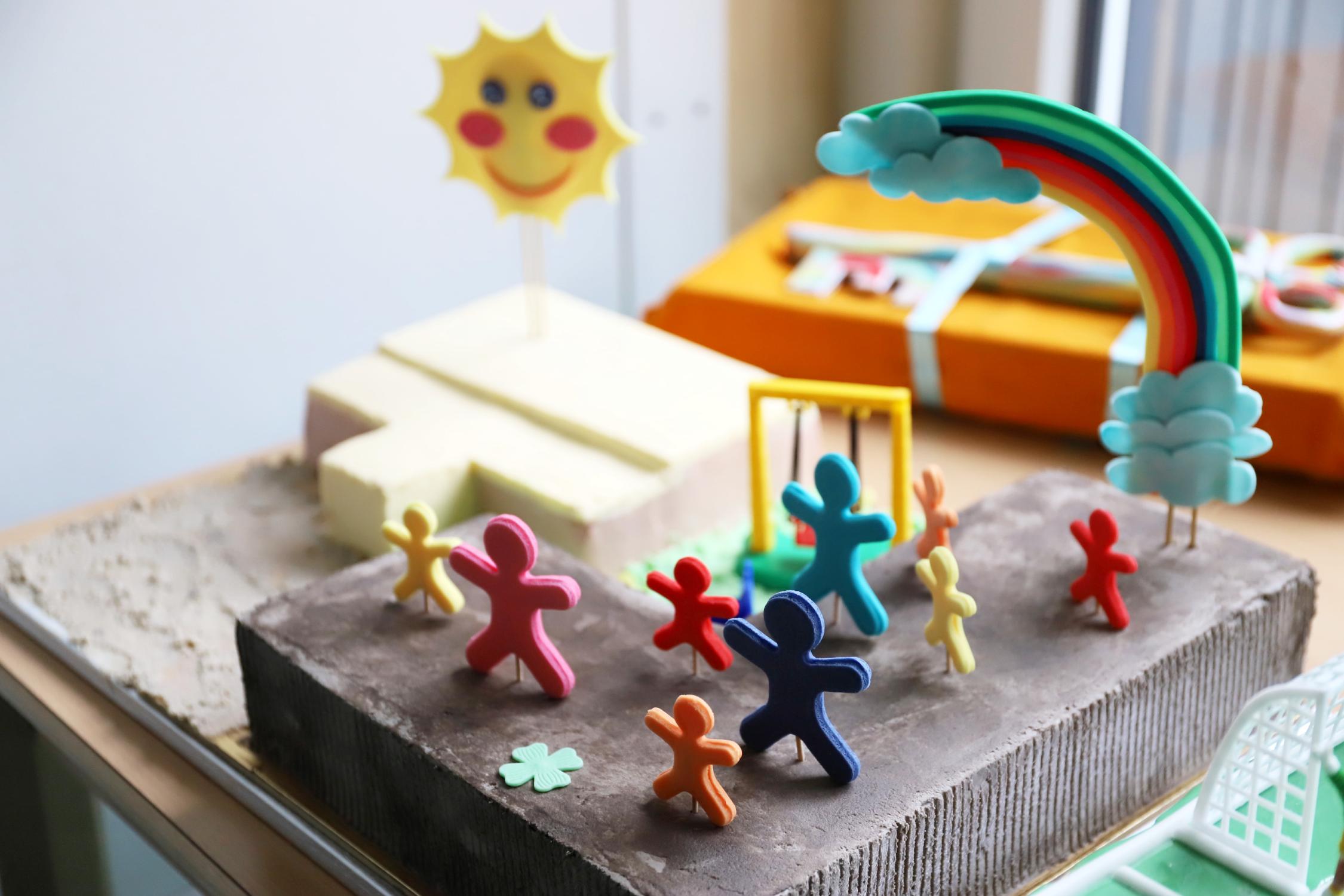 Dieser tolle Kuchen zeigt die Übergangskita, über der ein Regenbogen steht