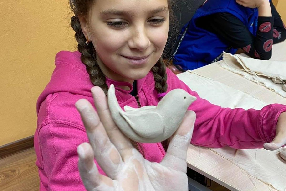 Ein kleines ukrainisches Mädchen hält eine Friedenstaube hoch