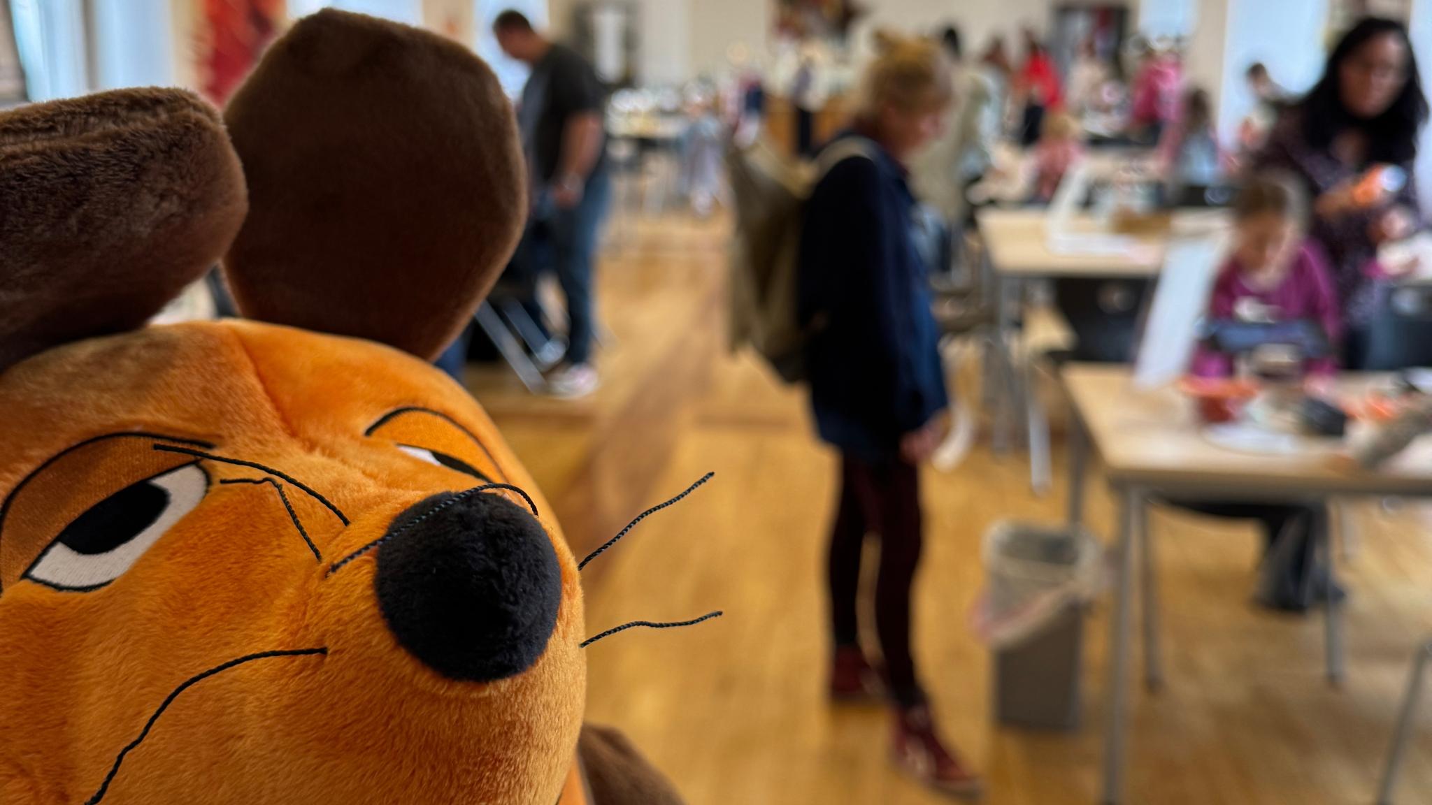 Die Maus ist zu sehen und im Hintergrund Menschen